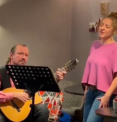 Sängerin mit pinkem Oberteil und ein Gitarrist mit akustischer Gitarre und einem Notenständer