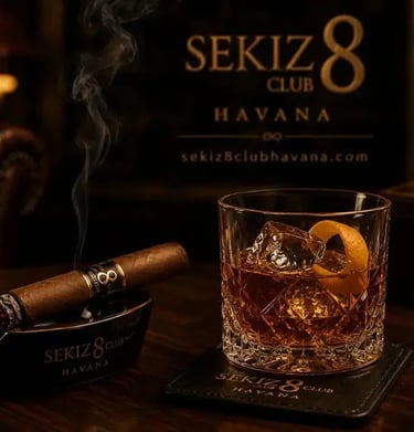 Una elegante copa de cóctel reposa sobre una mesa de madera oscura junto a un cigarro encendido.