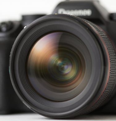 Close up of a camera lens reflecting a sun-drenched landscape, evoking the artist's perspective and warm cinematic style.