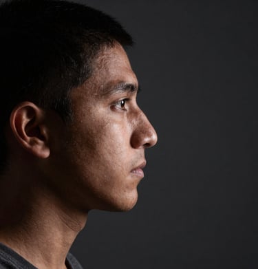 High-contrast photography of a subject's profile, illuminated by a sharp light source in a dark charcoal environment. The composition is clean and focused, typical of professional South American editorial work.