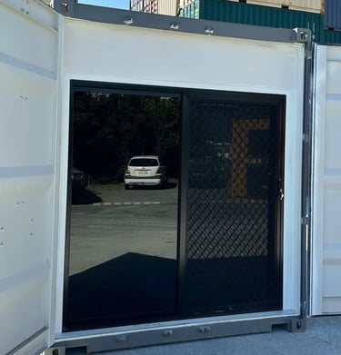 Modified shipping container with black sliding glass door and security screen mesh installed.