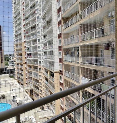 Balcony corner framed with grey pigeon netting blending subtly with building exterior.