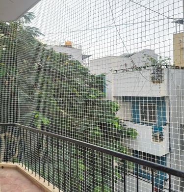Technician carefully fitting a pigeon net frame on a residential balcony in Mumbai.