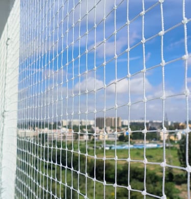  high-rise balcony in Wadala secured with Arjilli Safety Nets, with a clear blue sky background.