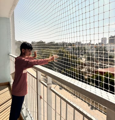 Technician installing durable pigeon netting on a balcony in a busy Mumbai neighborhood.