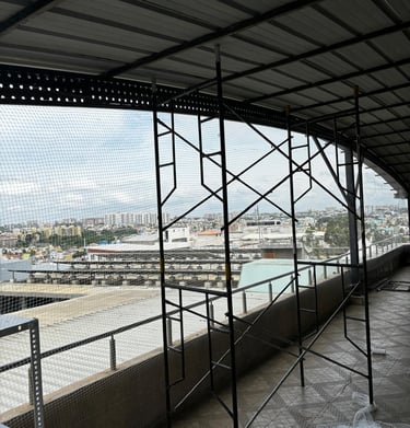 Technician carefully fitting pigeon netting along the warehouse roof edge to prevent bird entry.