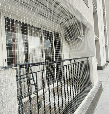 Balcony surrounded by safety nets with a cityscape of Mumbai in the background.