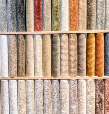 A wall display of colorful carpet samples and rug swatches in various textures and neutral tones.