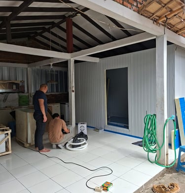 Technicians installing cold storage panel insulation in a white tiled warehouse area.