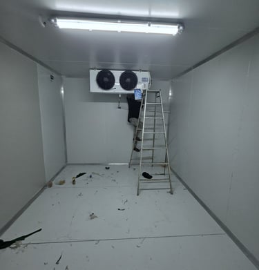 A technician installs a commercial refrigeration unit inside a walk-in cold storage room.
