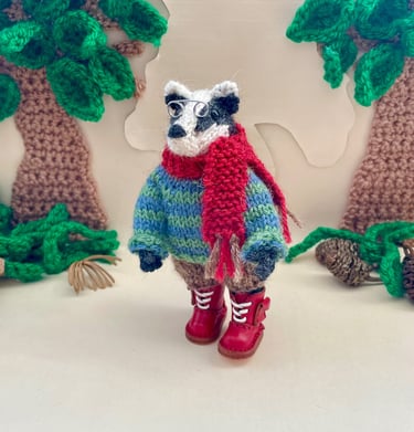 A little knitted badger ornament wearing a sweater and boots
