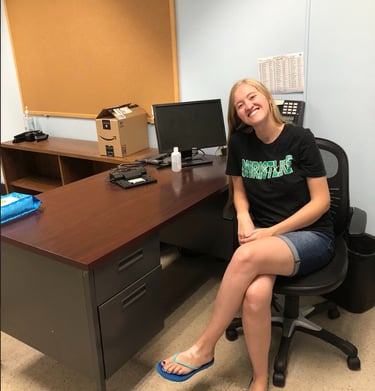 a teacher sitting at a desk with a clock on the wall