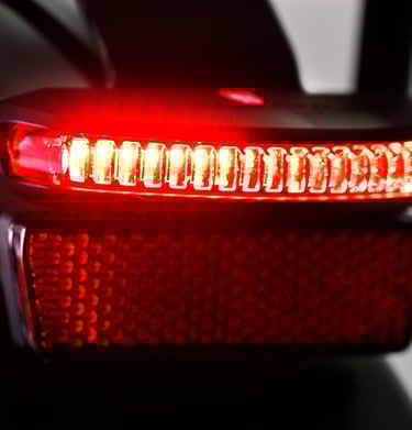 Close-up of a bright red LED bicycle tail light with a honeycomb reflector for night safety.