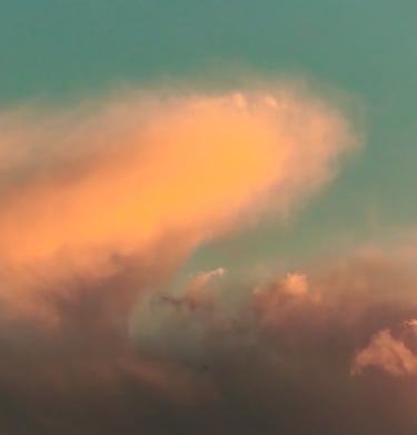 A closeup of a wave shape in the clouds in a blue sky at sunset.