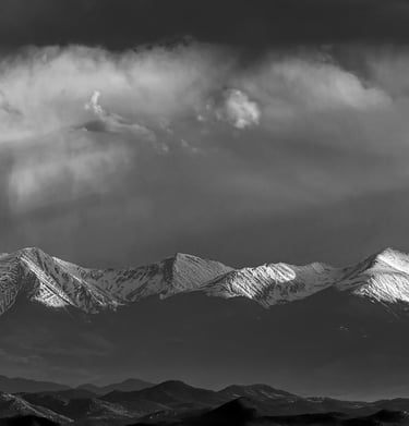 A black-and-white photograph of storm clouds above a mountain range in Victor, Colorado.