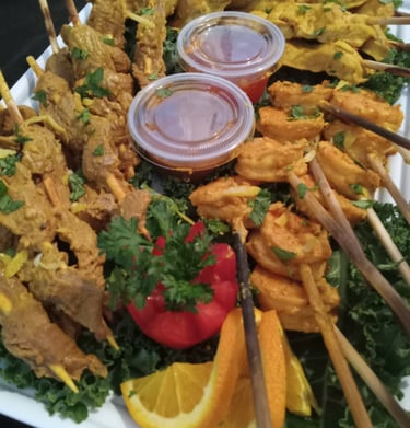 a platter of food with chicken, beef and shrimp satays