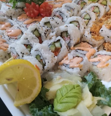 a plate of sushi rolls with a lemon wedged in the middle