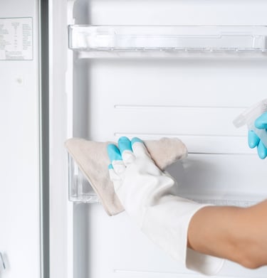 a person in a white shirt and gloves cleaning a refrigerator
