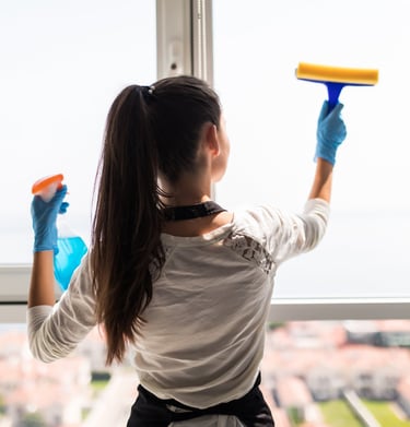 a woman in a white shirt and gloves holding a blue cleaning sponge