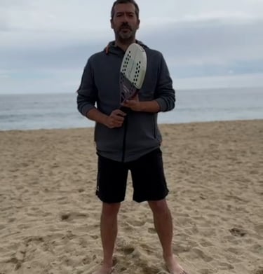 a man holding a tennis racket on a beach