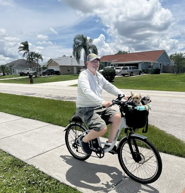 Robert riding a bicycle with a dog in a basket