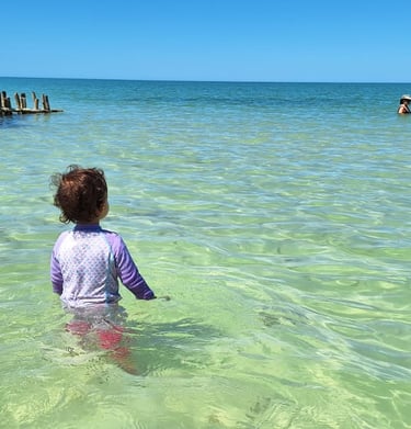 a child in the water with a man in the background