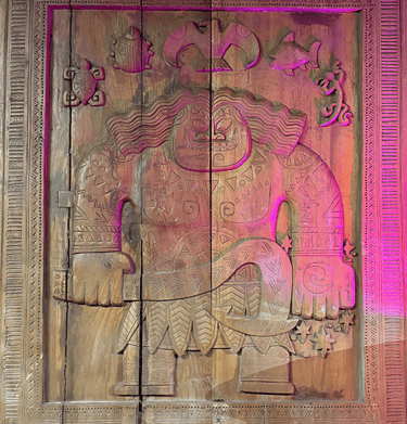 Polynesian wood carving of Maui holding a fishhook, featuring tribal tattoos and ocean animal motifs.