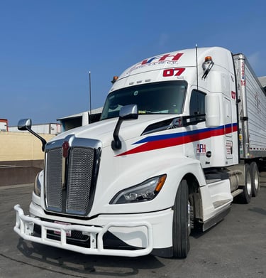 Camión refrigerado AFH Logistics con logotipo rojo y azul estacionado en pavimento