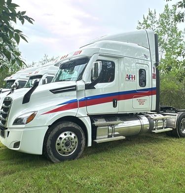 Camión AFH Logistics con remolque aparcado junto a césped y árboles