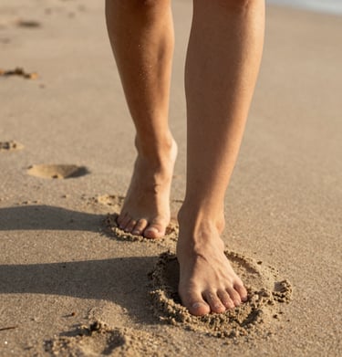 Detail shot of feet walking on a North American / US beach, soft sand textures, warm golden light, cinematic style.