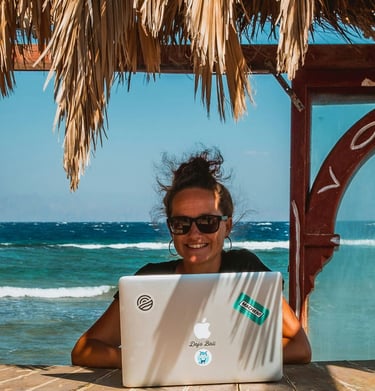 Digital nomad woman learning spanish on a laptop at a tropical beach office with ocean views.