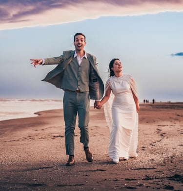 Pareja feliz corriendo en la playa después de boda, fotografía natural y espontánea en Pinamar