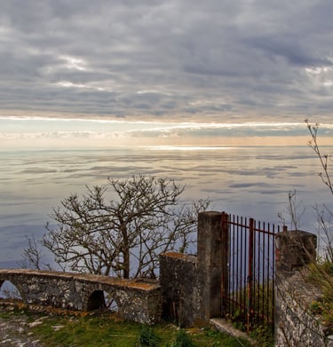 Vista panoramica di Maratea da un balcone in pietra con un cancello sotto un cielo nuvoloso