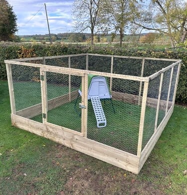 Large wooden chicken run with wire mesh and a small coop on a green lawn.