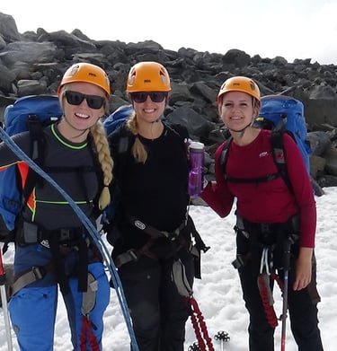 three female climbers standing standing in the snow