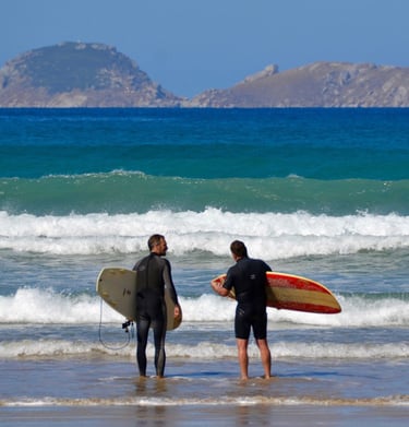 two surfers standing in the surf at the beach