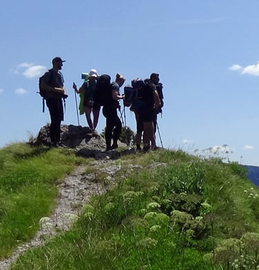 six trekkers standing at the top of a distant hill