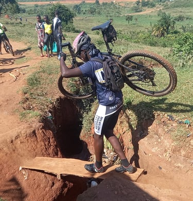 a man carrying a bicycle on a dirt road