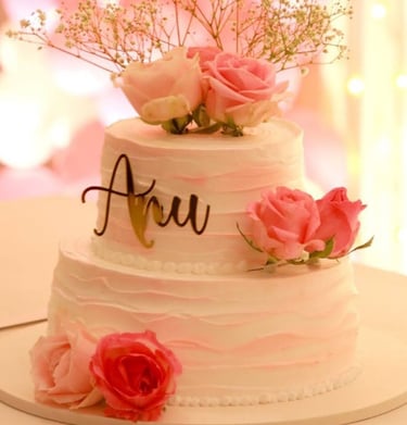 Elegant two-tier white and pink ombré cake decorated with fresh roses and a custom script topper.