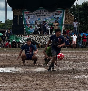Athletes playing soccer on a muddy field during the Copa Indigena 2025 indigenous people's football tournament.