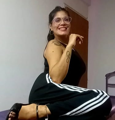 Tama masajes sensuales Palermo, sentada con outfit deportivo y anteojos en su espacio de relax.