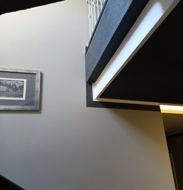 Modern minimalist staircase interior featuring geometric wall angles and a framed black and white picture.