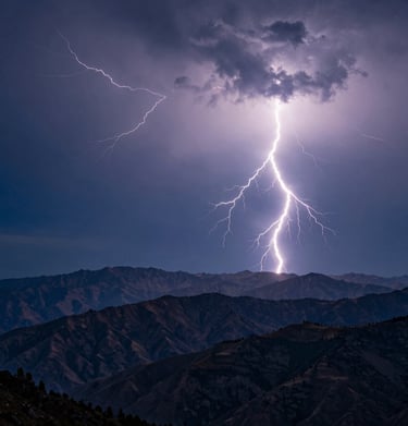 A wide-angle photography shot of multiple lightning bolts spidering across a dark steel blue sky over a mountain range, International / Western.