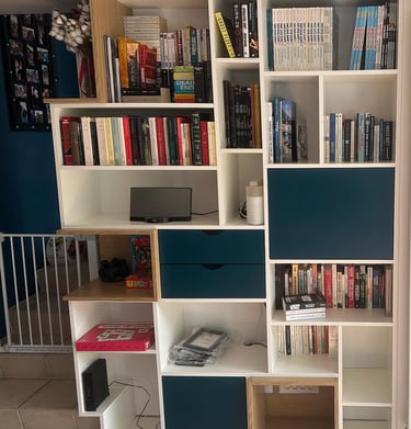 a bookcase with a television and a laptop on the floor