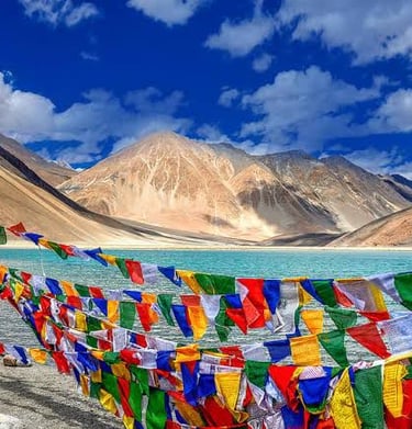 Colorful Buddhist prayer flags fluttering by the turquoise Pangong Lake in the Ladakh Himalayas.