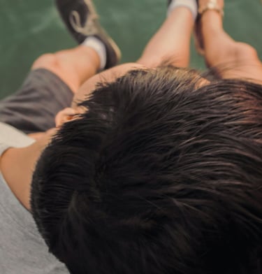 Couple enlacé, vu du dessus, assis sur un ponton en bois, les jambes au dessus de l'eau..
