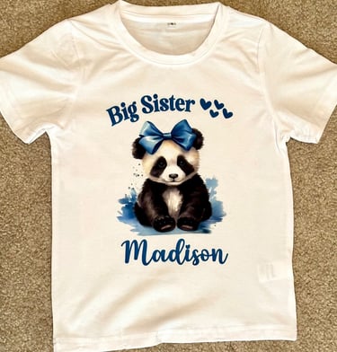 White childs t-shirt with a Panda Bear wearing a blue bow, reading "Big Sister" & personalized with childs name.