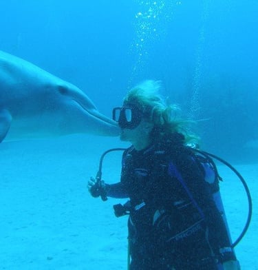 Bahamas Fixer Sarah Hamilton with a dolphin giving her a kiss while diving