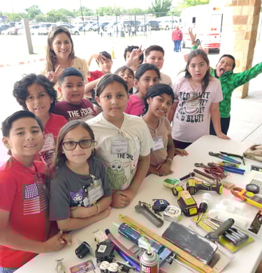 students are around a table with home remodel tools and material for them to see touch & questions