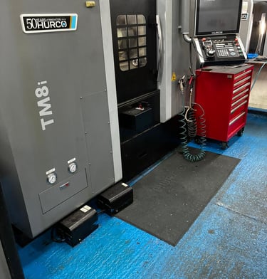 A Hurco TM8i CNC lathe machine in a workshop with a red tool chest and digital control panel.